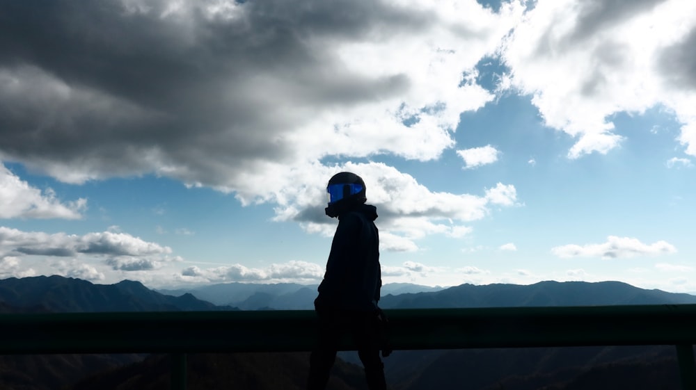 a person standing on top of a hill under a cloudy sky