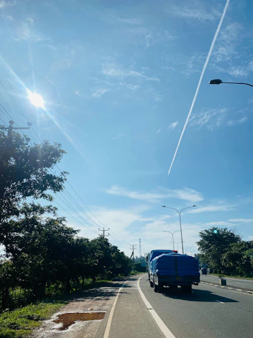 A sturdy container truck navigating a busy highway under a clear sky.