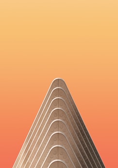 A minimalist architectural structure with a triangular, layered design set against a gradient orange background.