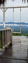 A wooden deck with comfortable chairs overlooking a misty mountain valley.