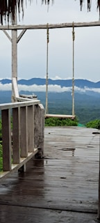 A wooden deck with comfortable chairs overlooking a misty mountain valley.