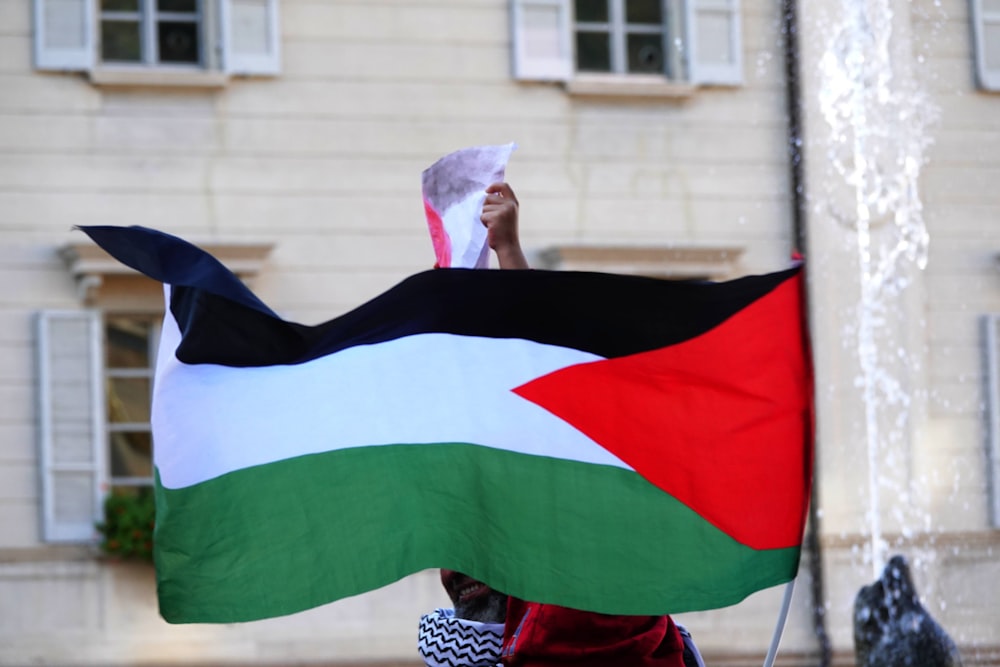 a person holding a flag in front of a building