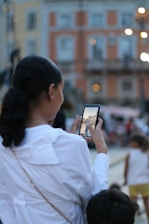 A smiling influencer filming content with a smartphone in a stylish urban setting.