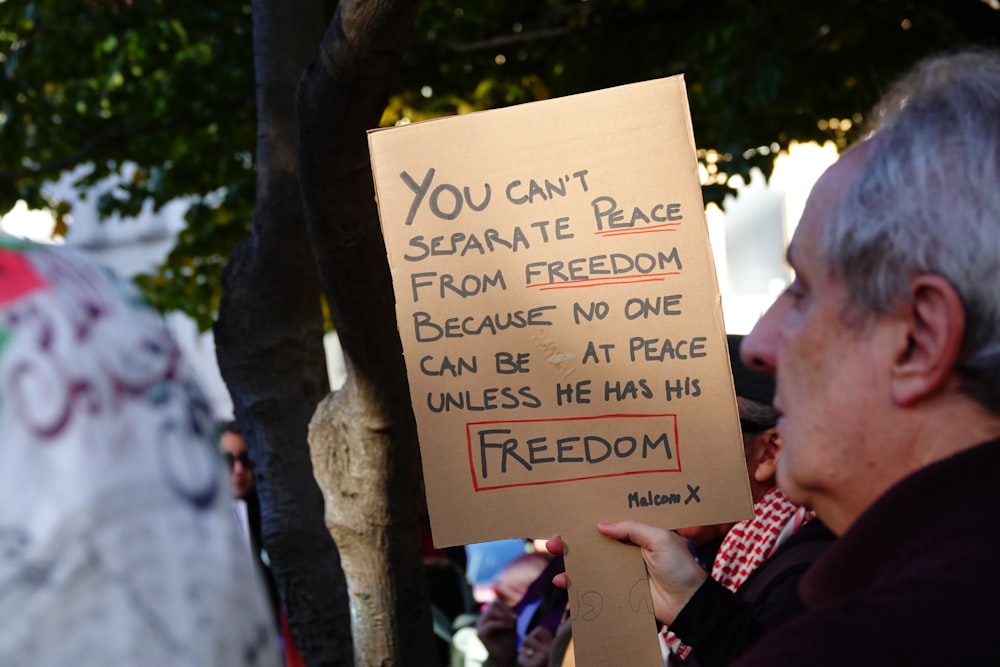 a man holding a sign that reads you can't sesamete bag from freedom