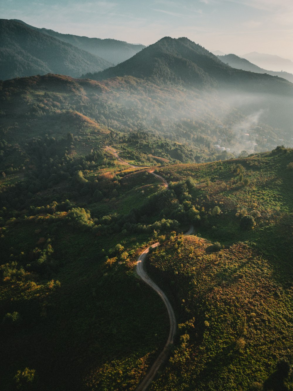 a winding road winding through a lush green valley