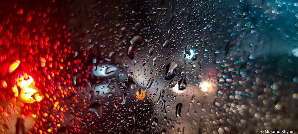 rain drops on a window with a red light in the background