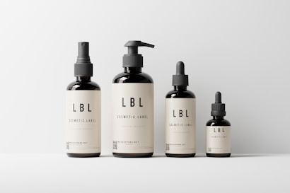 Four cosmetic bottles of varying sizes are neatly arranged against a plain background. Each bottle features a minimalist beige label with the text 'LBL Cosmetic Label' and a small QR code at the bottom.
