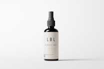 A minimalistic cosmetic bottle with a pump dispenser is positioned centrally against a plain white background. The bottle is dark in color with a simple, elegant label that reads 'LBL COSMETIC LABEL'. The design emphasizes clean lines and simplicity, highlighting the brand's focus on elegance and modern aesthetics.