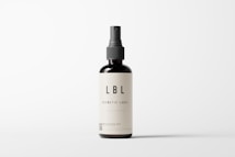 A minimalistic cosmetic bottle with a pump dispenser is positioned centrally against a plain white background. The bottle is dark in color with a simple, elegant label that reads 'LBL COSMETIC LABEL'. The design emphasizes clean lines and simplicity, highlighting the brand's focus on elegance and modern aesthetics.