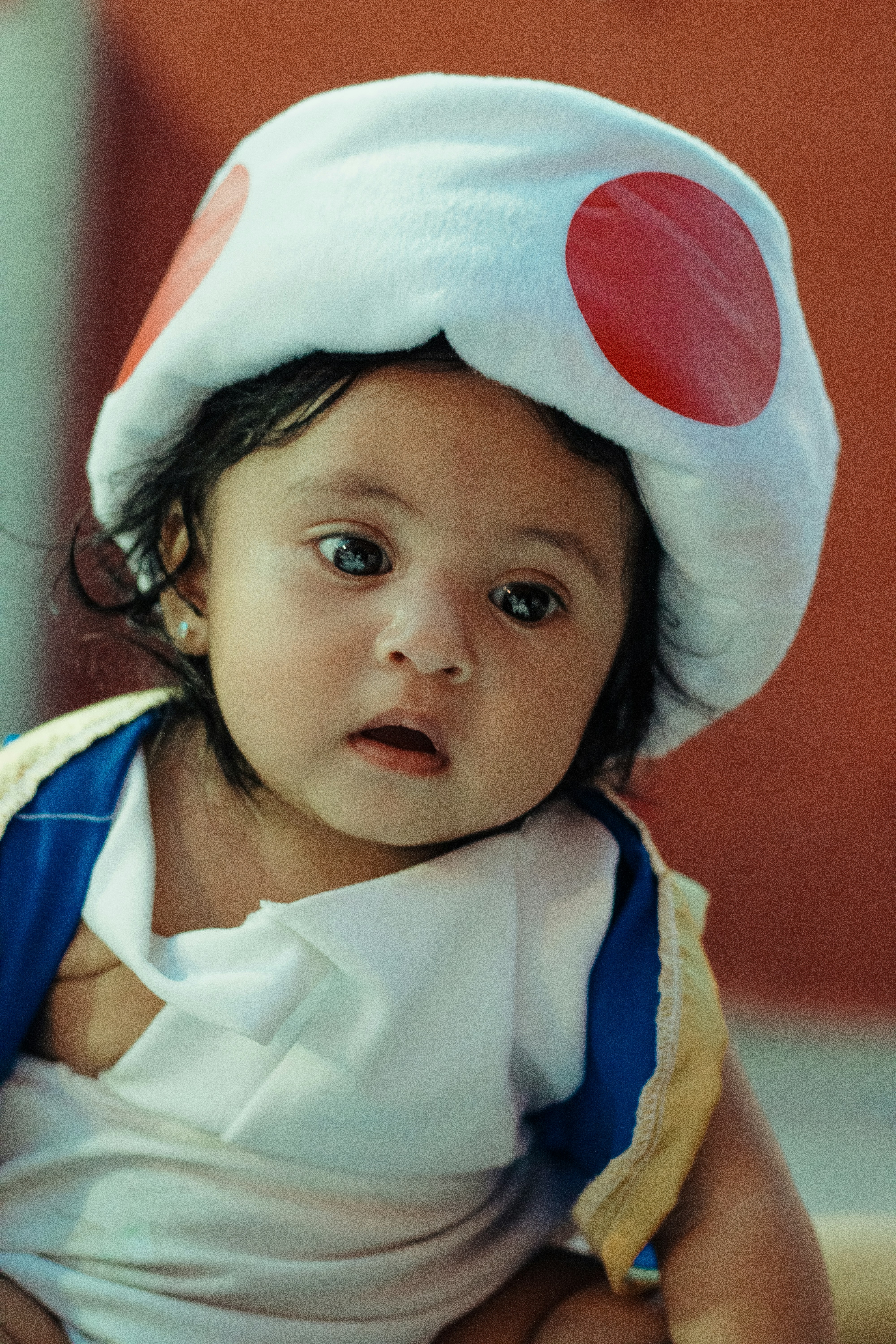 seorang anak kecil mengenakan topi putih dengan titik merah di atasnya