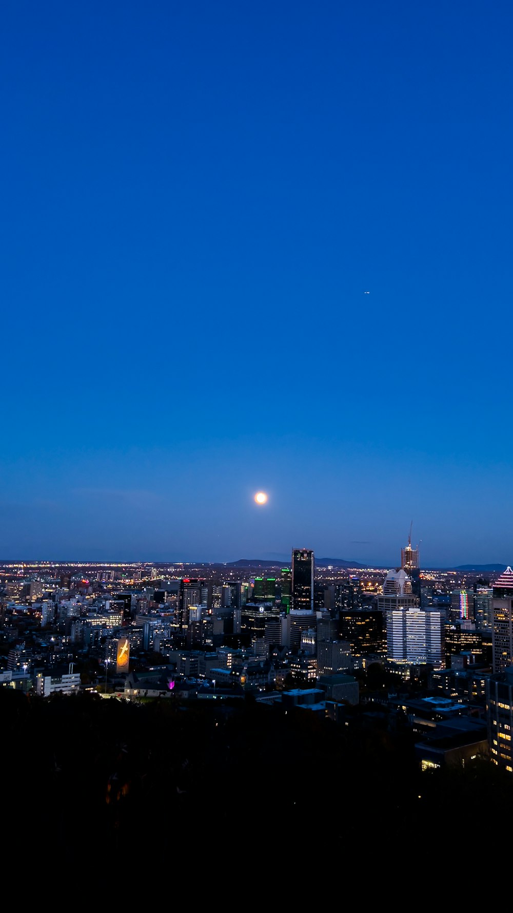 a view of a city at night with the moon in the sky