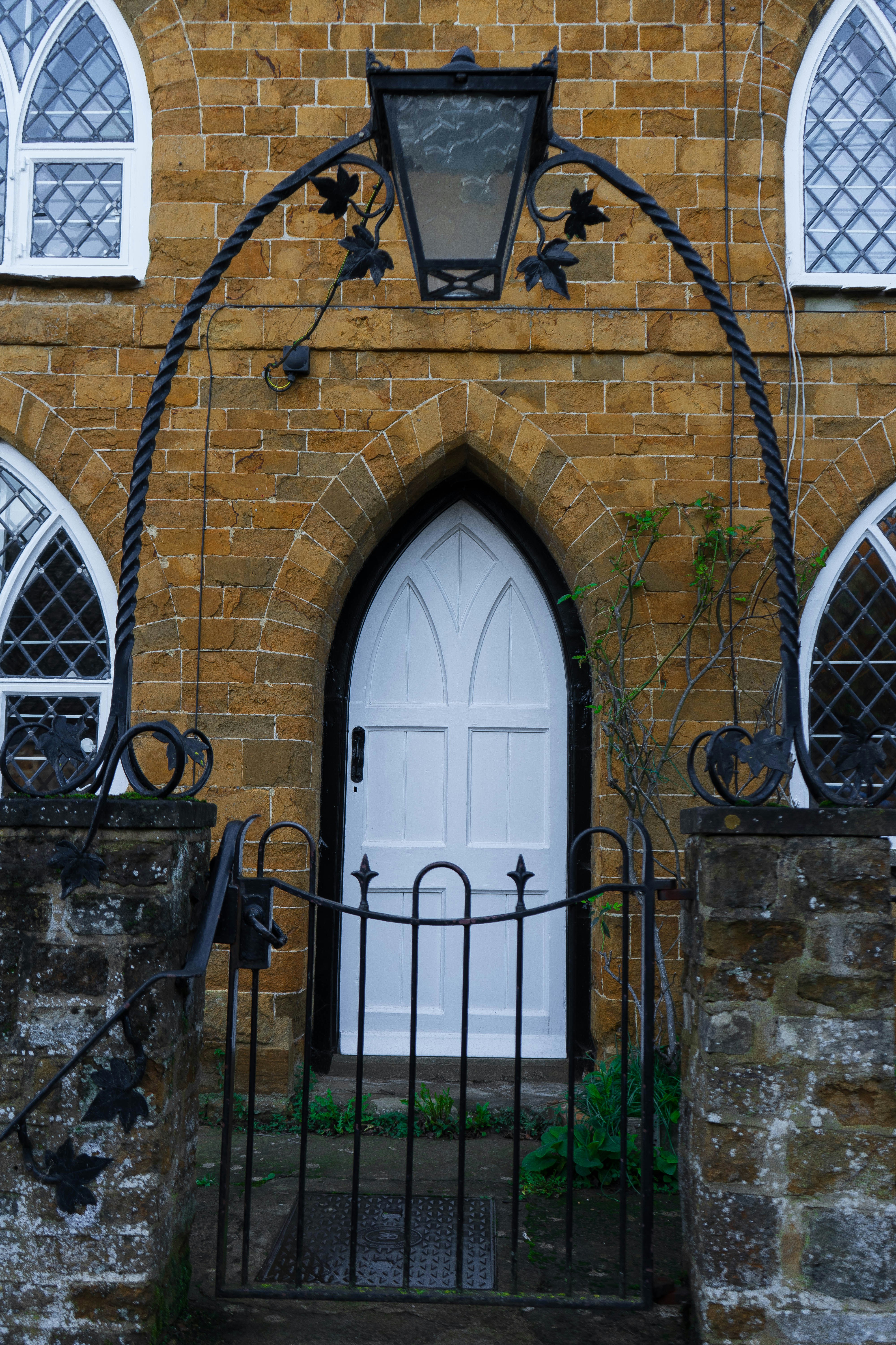a brick building with a white door and a wrought iron gate