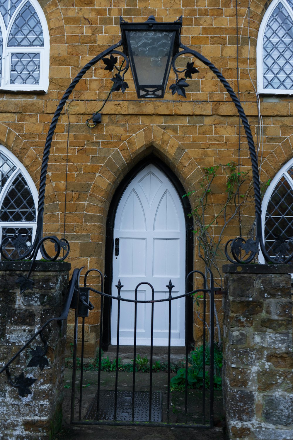 a brick building with a white door and a wrought iron gate