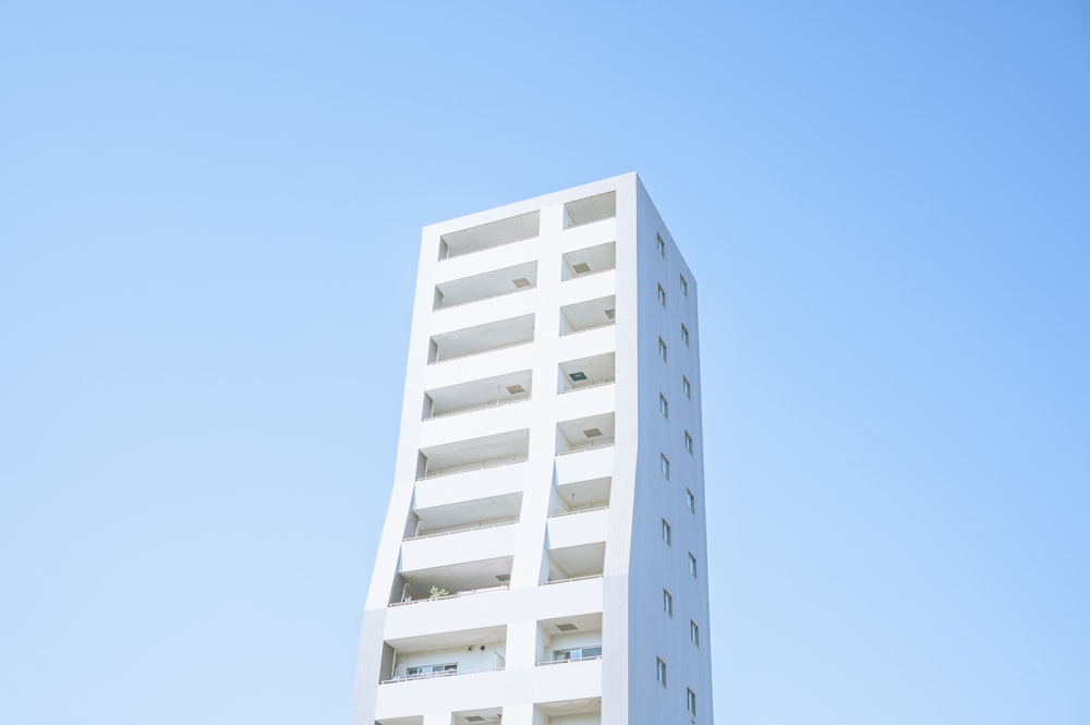 a tall white building with balconies on top of it