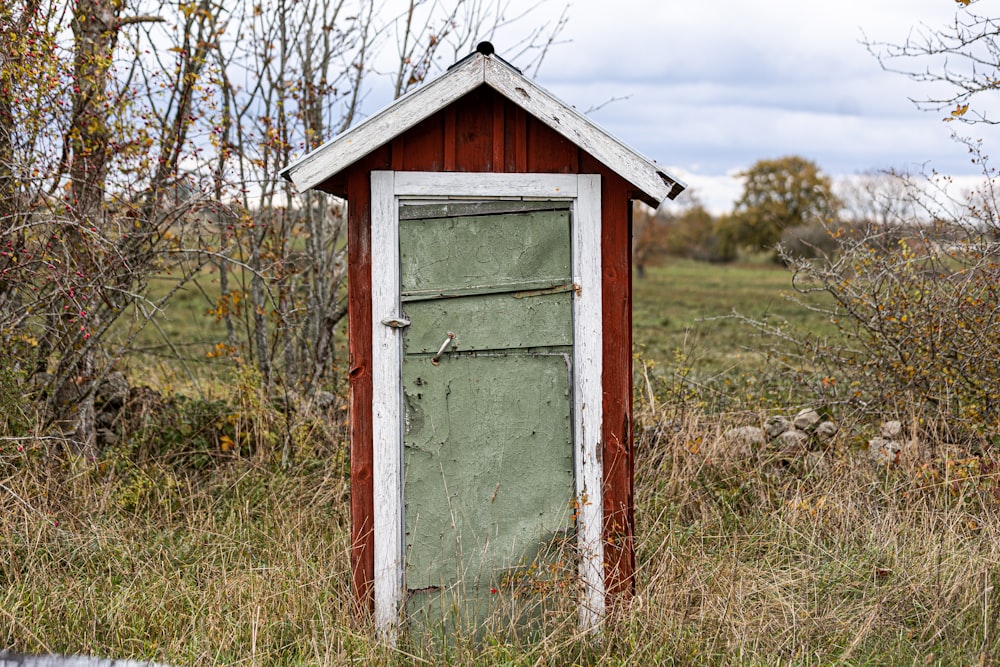 an outhouse in the middle of a grassy field