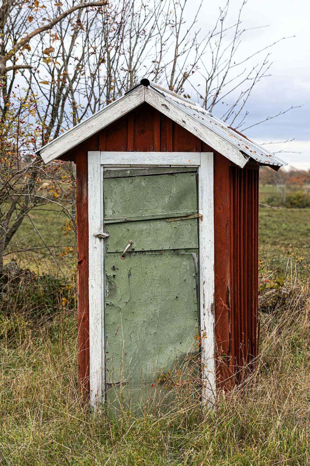 une toilette extérieure dans un champ avec une porte ouverte