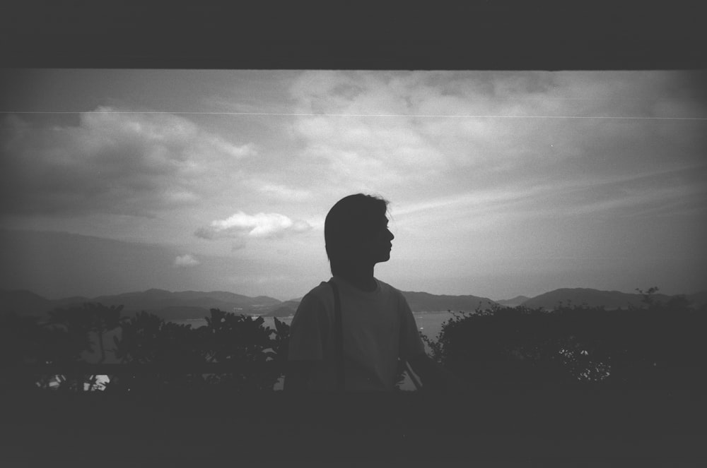 a man standing in front of a cloudy sky