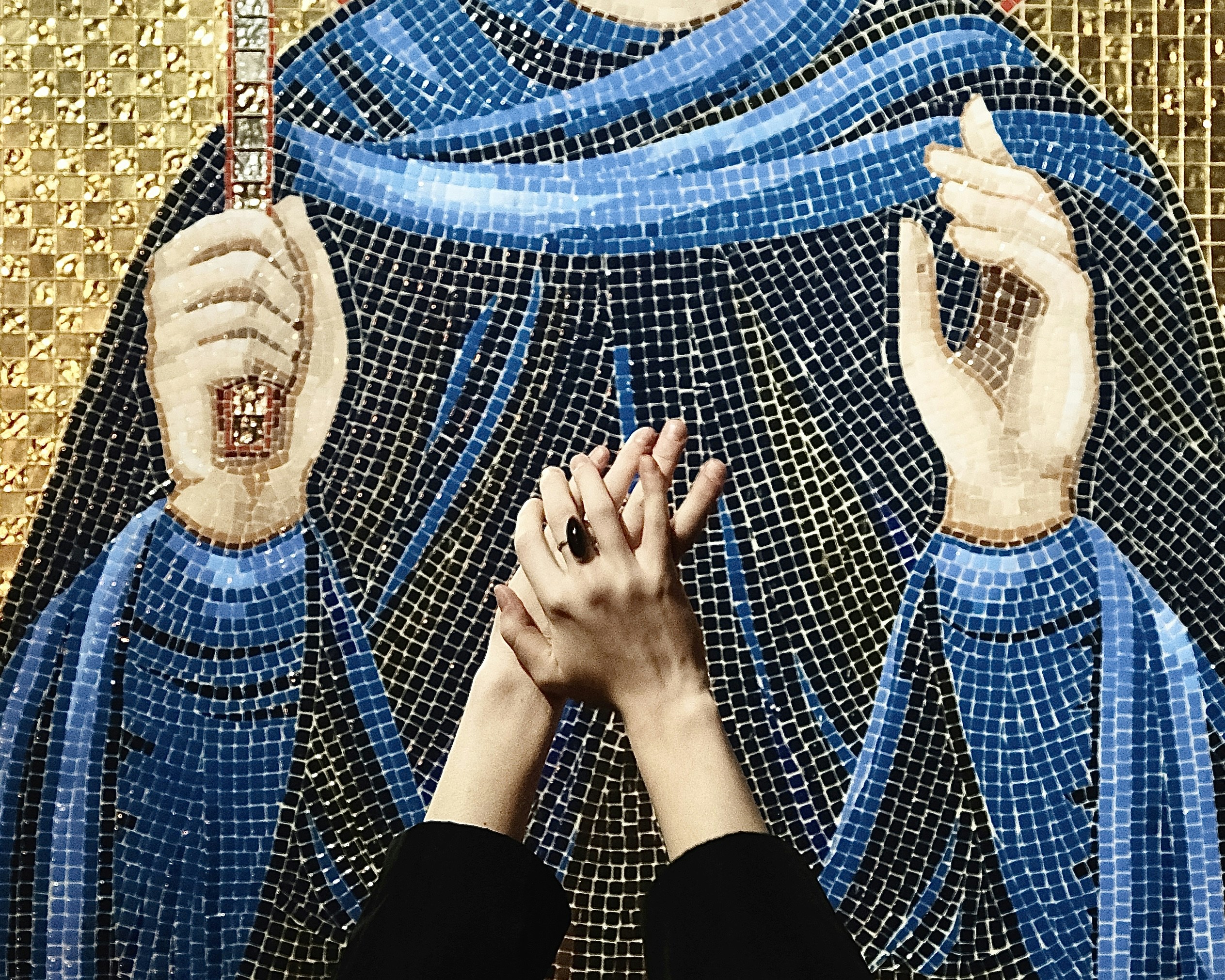 two hands touching each other in front of a painting