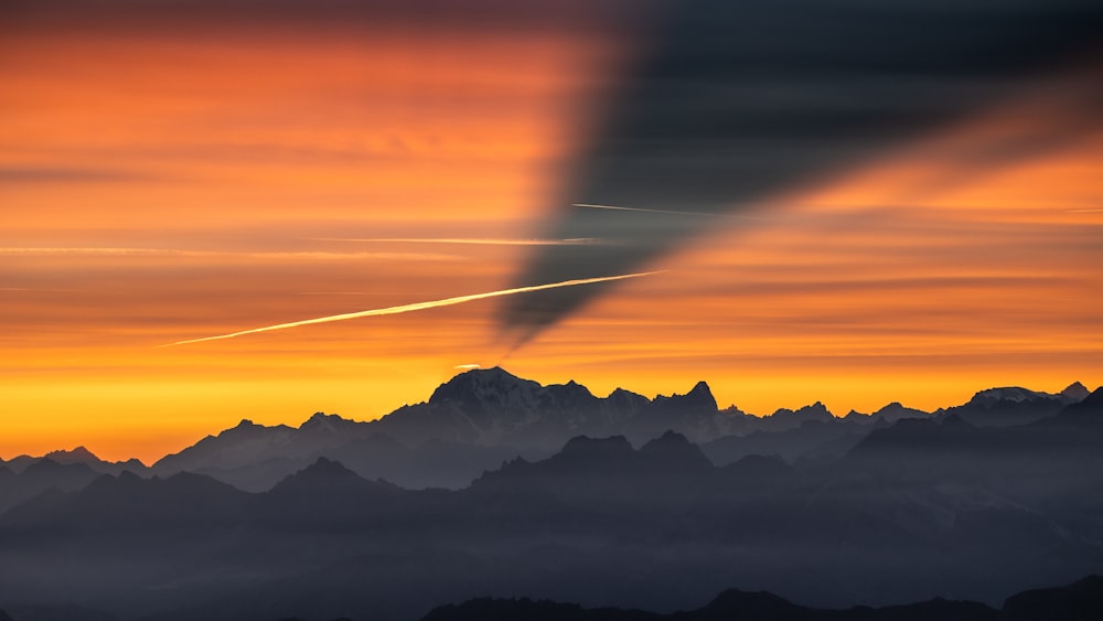 a plane flying over a mountain range at sunset