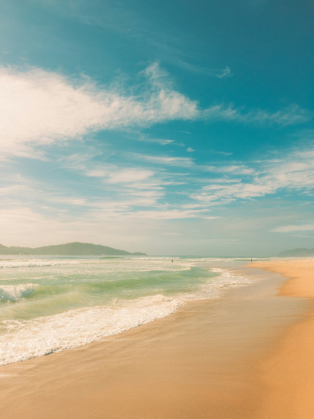 a sandy beach with waves coming in to shore