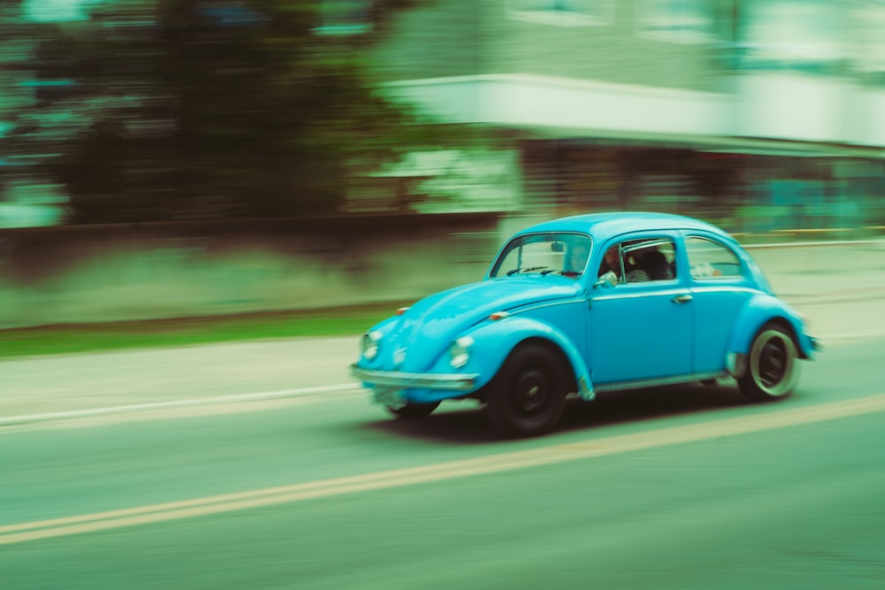 a blue car driving down a street next to a tall building