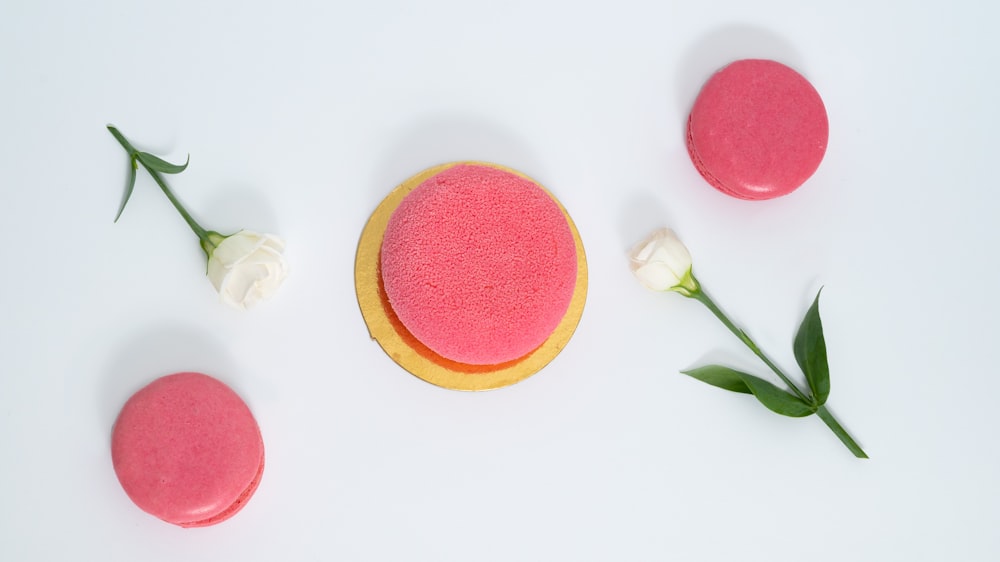 a pink and yellow cake next to a white rose