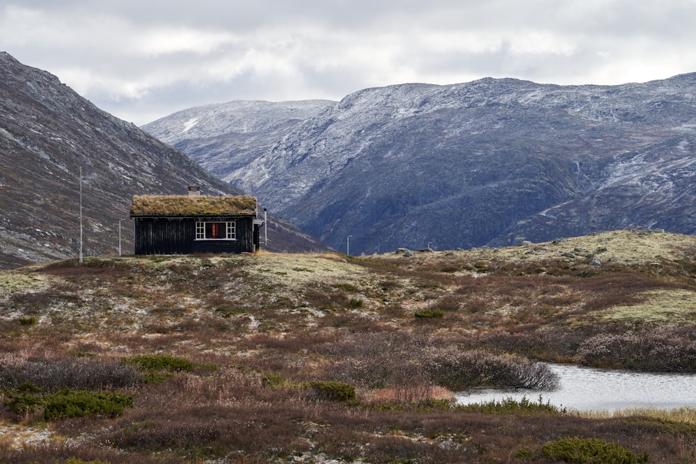 a small cabin in the middle of a mountain range