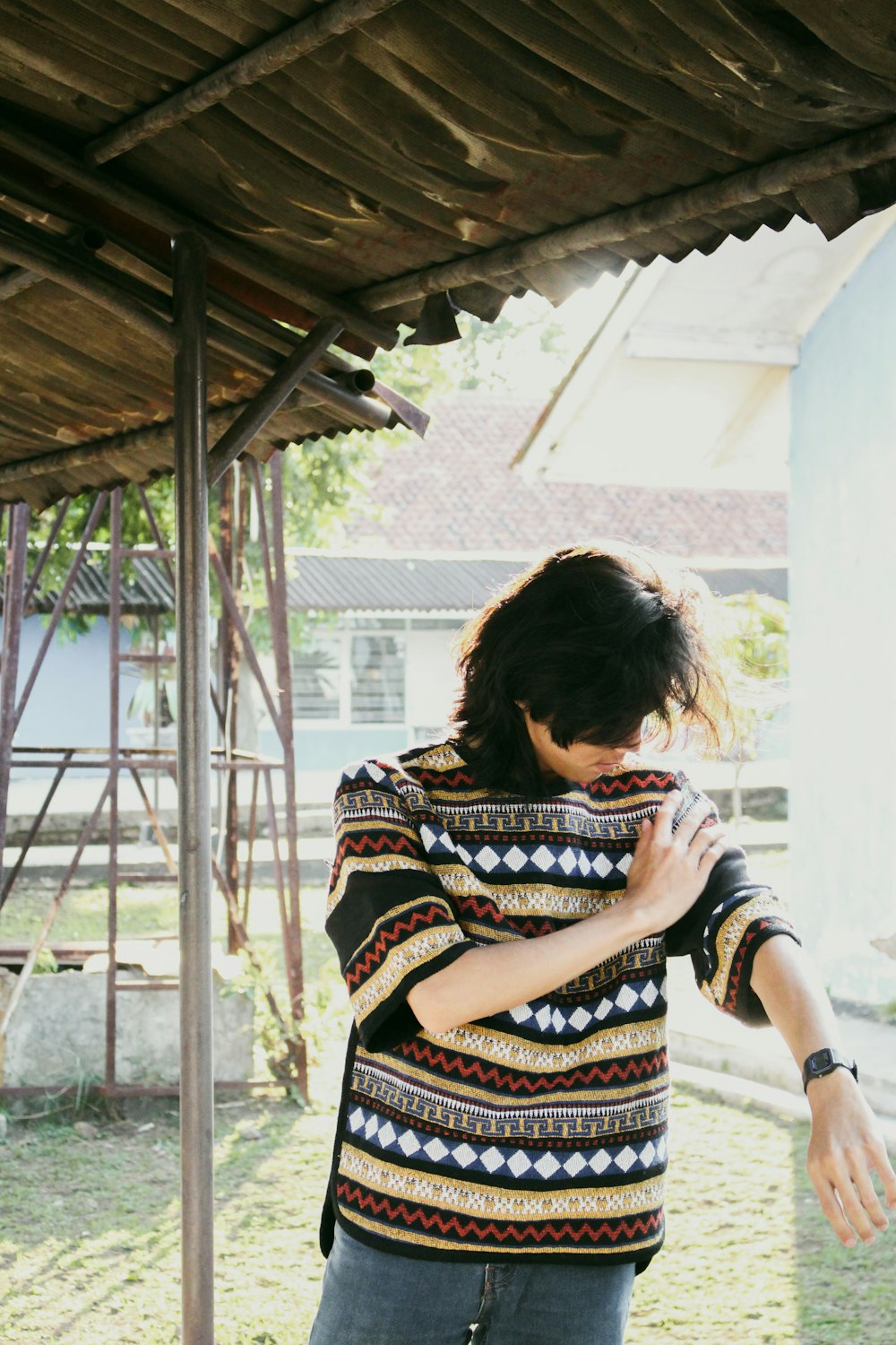 a woman standing under a wooden structure holding a skateboard