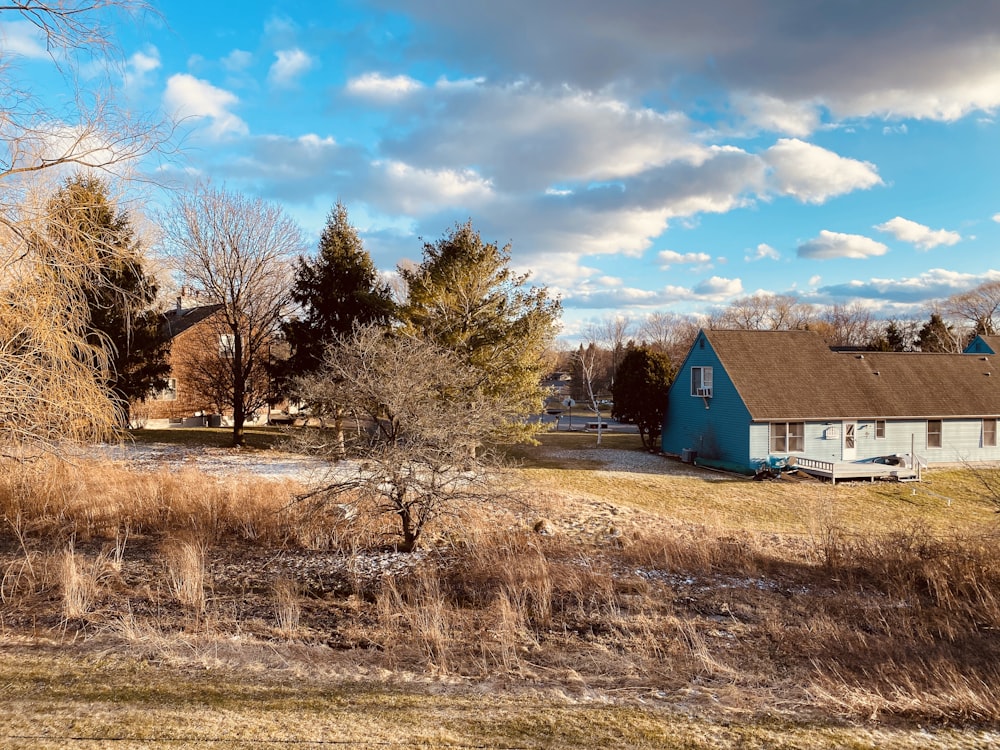 a blue house sitting in a field next to a forest