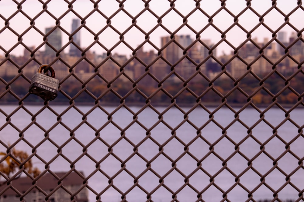 a lock on a chain link fence with a city in the background