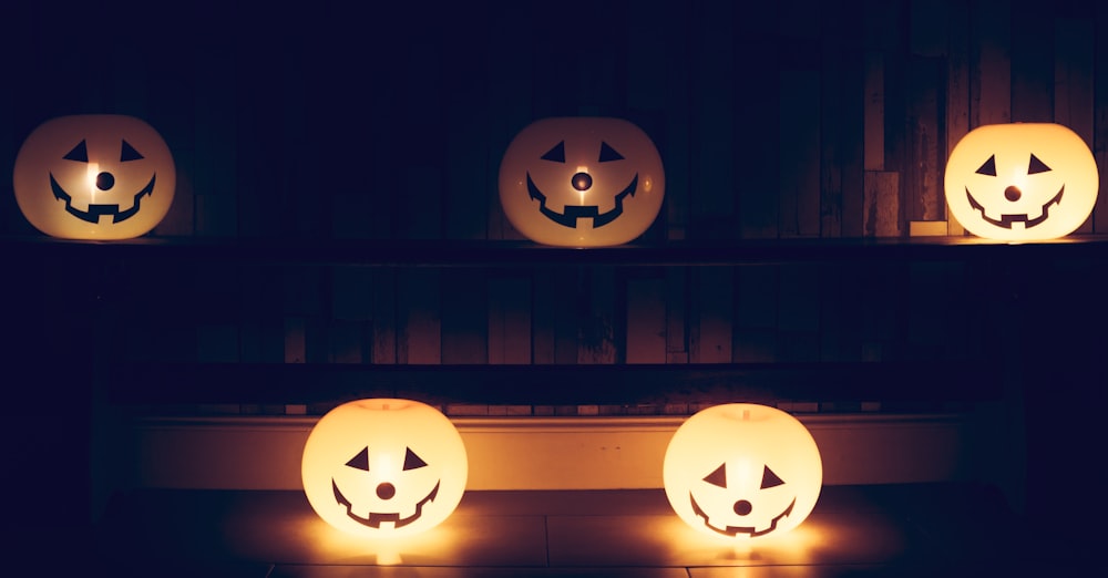 three pumpkins with faces carved into them sitting on a shelf