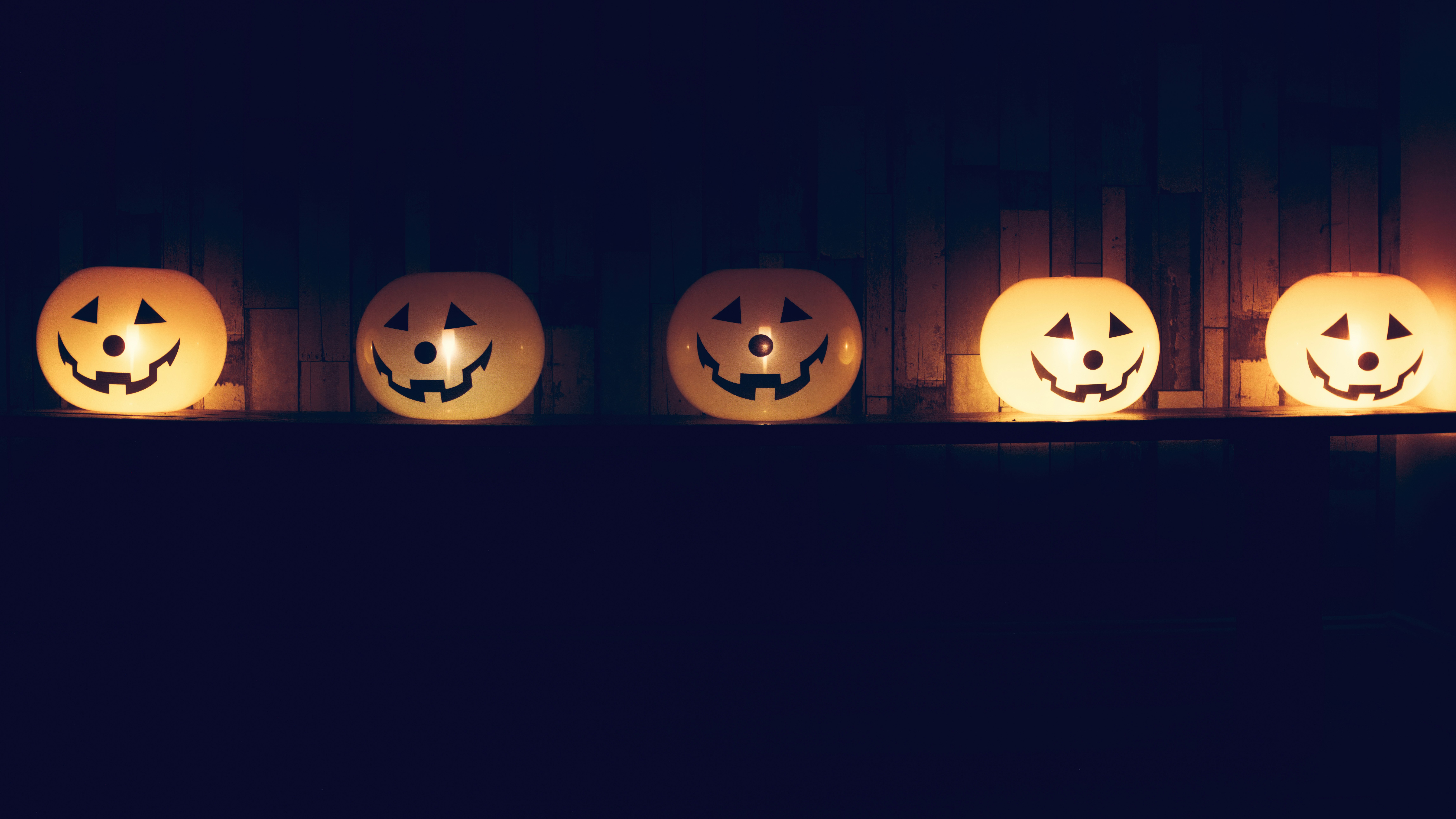 a row of carved pumpkins sitting on top of a shelf