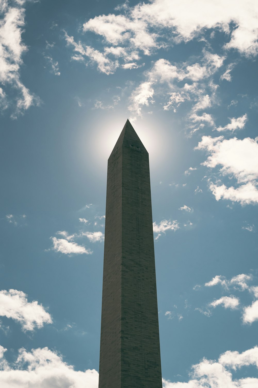 the washington monument is silhouetted against a partly cloudy sky