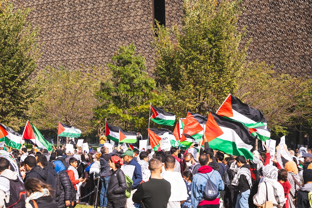 um grande grupo de pessoas segurando bandeiras em frente a um prédio