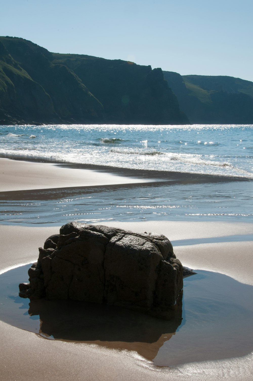 a rock sitting on top of a sandy beach