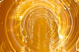 A vivid display of swirling lights creating circular patterns, resembling a tunnel or vortex effect with a golden hue.