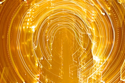A vivid display of swirling lights creating circular patterns, resembling a tunnel or vortex effect with a golden hue.