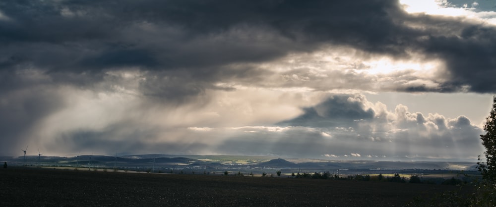 the sun shines through the clouds over a field