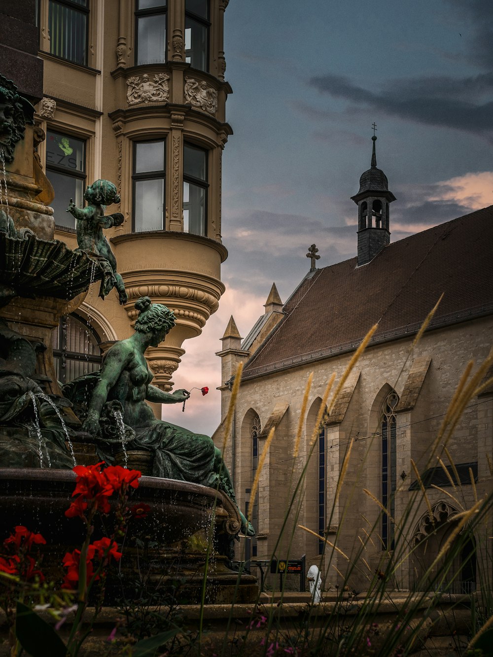 a fountain in front of a building with a clock tower in the background