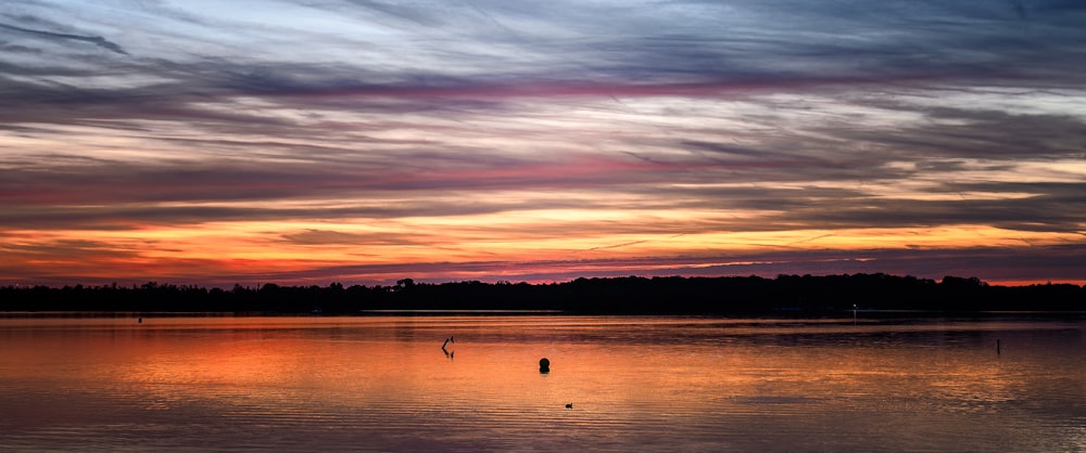 a sunset over a body of water with trees in the background