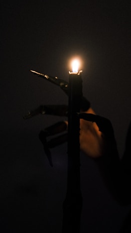 A moody vignette featuring a skull candle holder casting flickering shadows on a rustic wooden table.