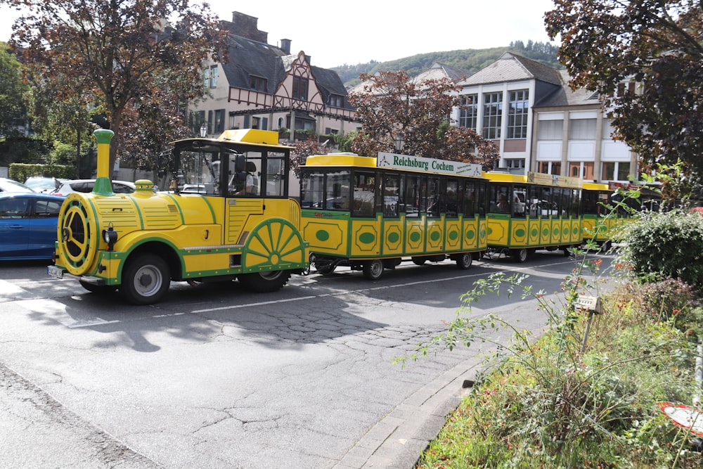 a yellow and green train traveling down a street
