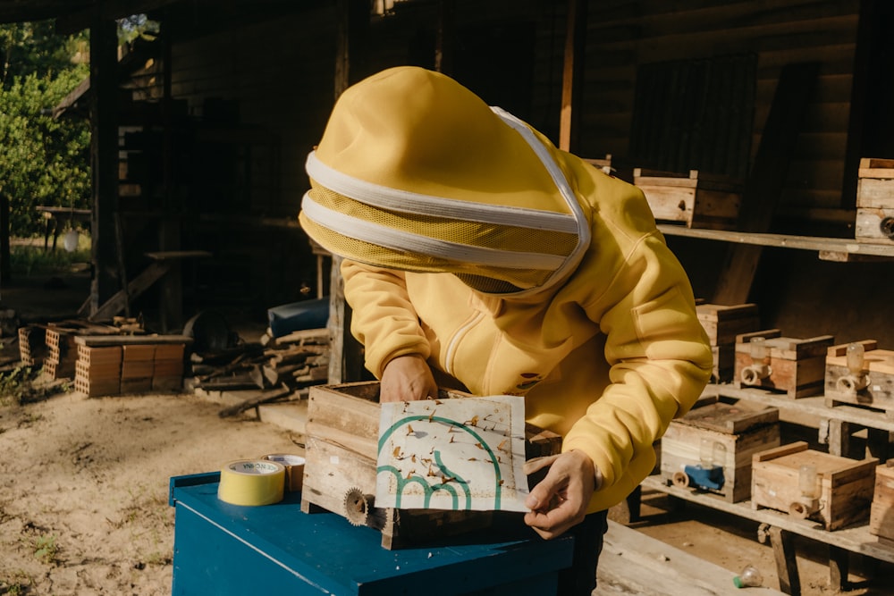 a person in a yellow jacket is painting a picture