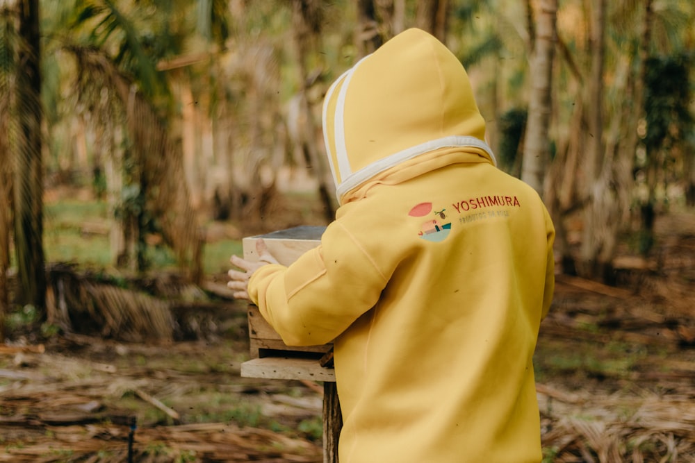 a person in a yellow jacket standing in a forest