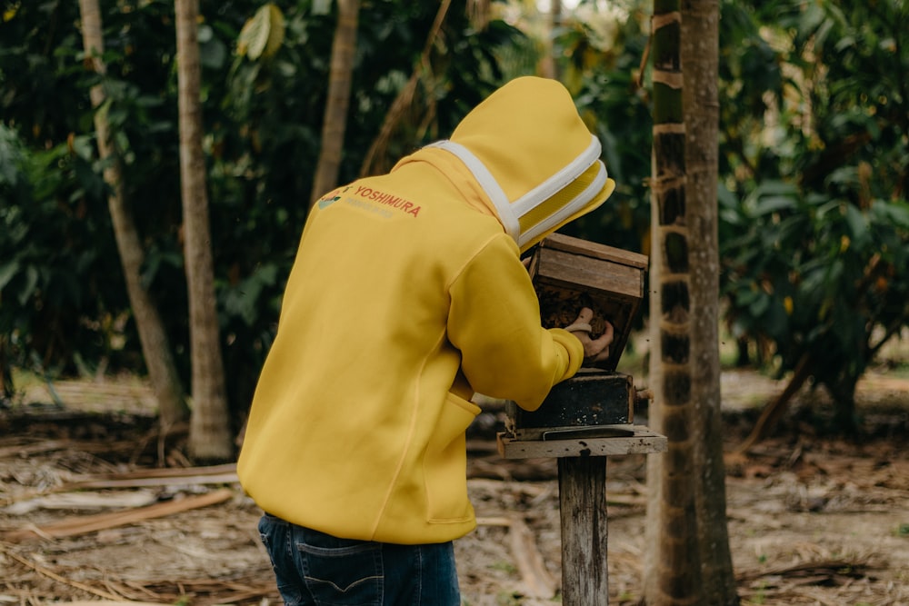 a person in a yellow jacket is working on a piece of wood