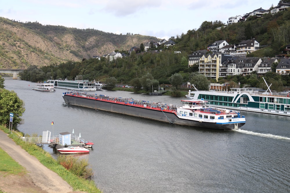 a large boat traveling down a river next to a lush green hillside