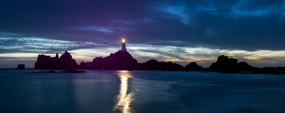 a lighthouse is lit up at night on the beach