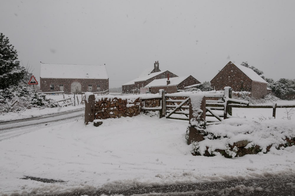 a snow covered street with a fence and a church in the background