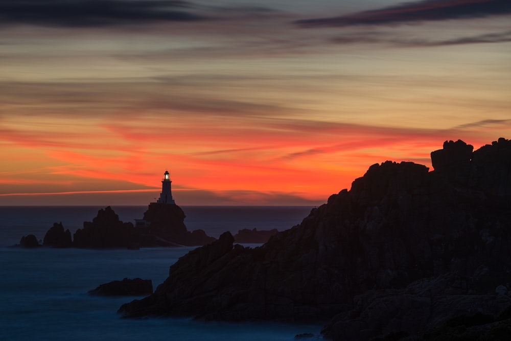 a lighthouse on a rocky outcropping at sunset