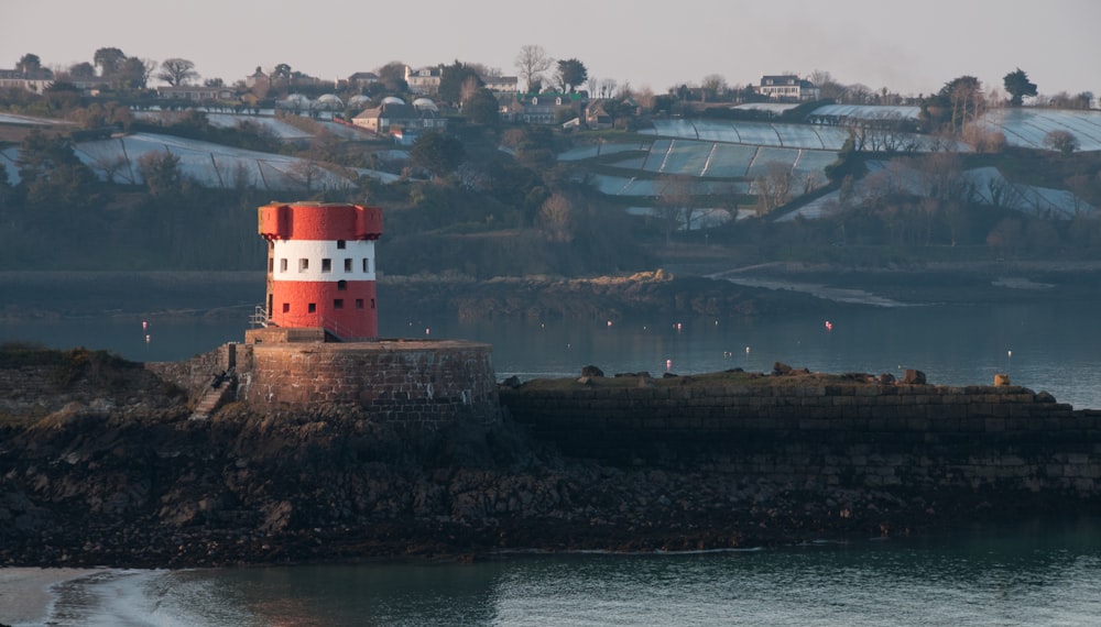 a red and white lighthouse sitting on top of a rock